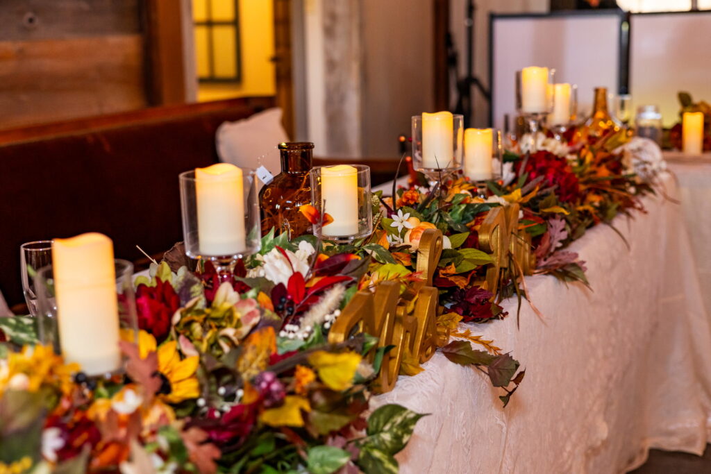 Wedding head table with autumn florals and candles at a rustic barn venue