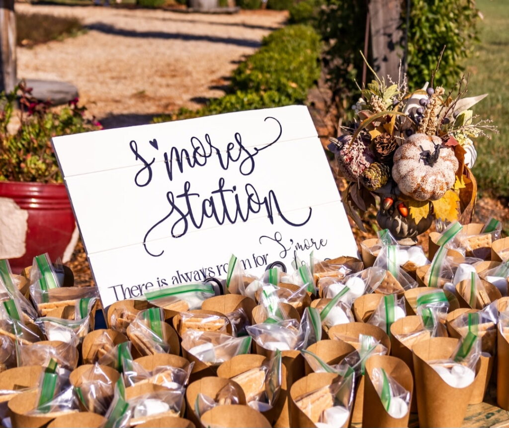 Smores station wedding favor table with kraft bags and a hand-lettered sign