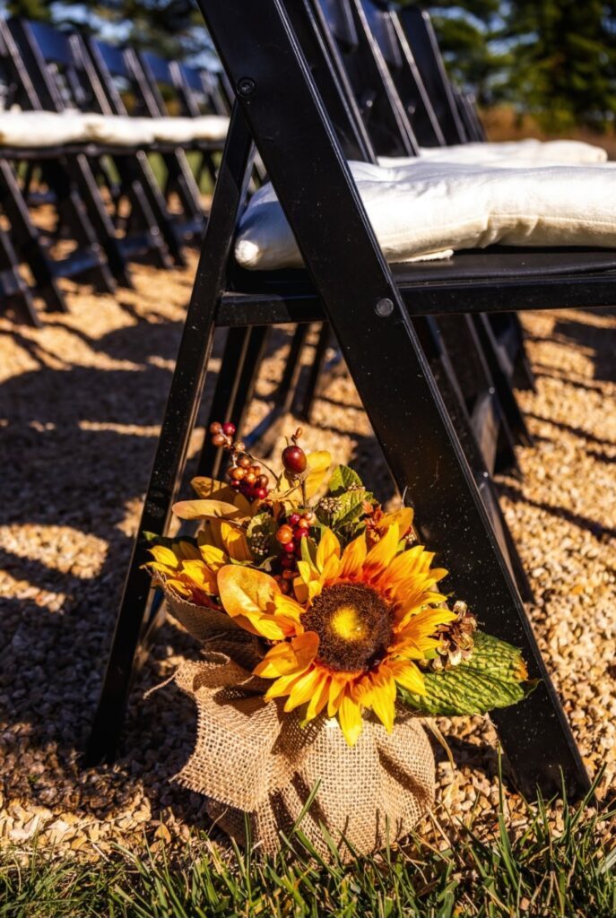 Sunflower aisle decor on a chair at an outdoor wedding ceremony